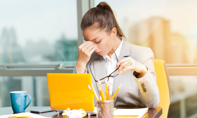 Donna stressata alla scrivania che ha bisogno di tecniche di rilassamento rapido per ridurre lo stress in estate.